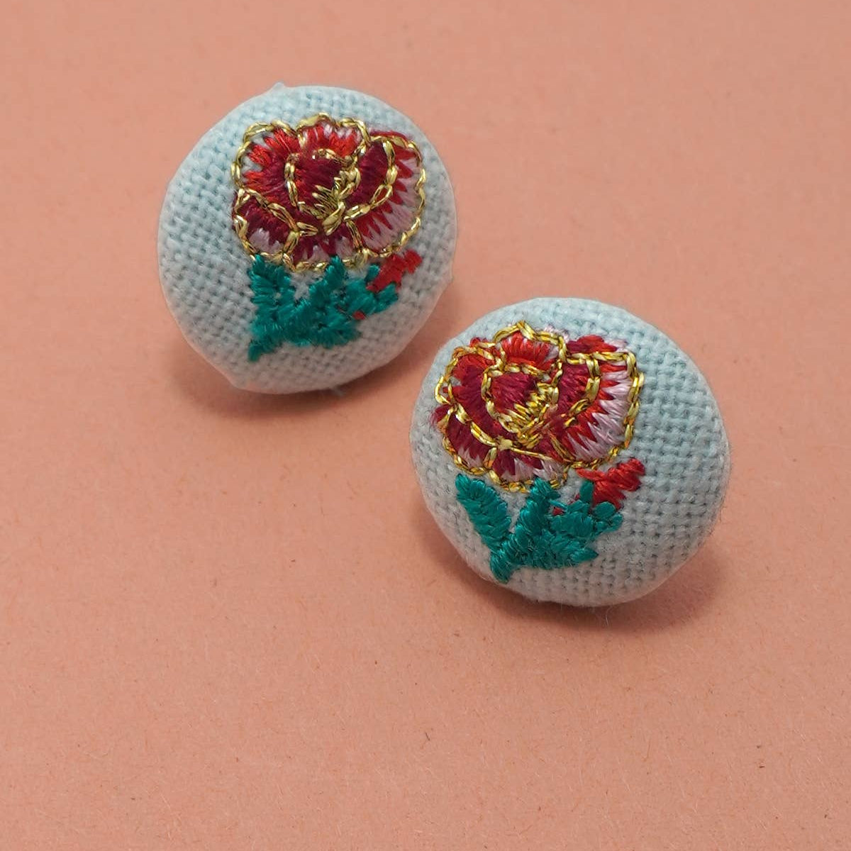 Two embroidered floral buttons on a pink background