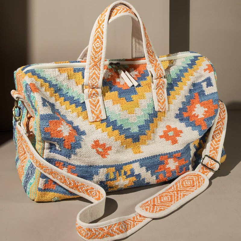 Colorful patterned handbag with a strap on a neutral background