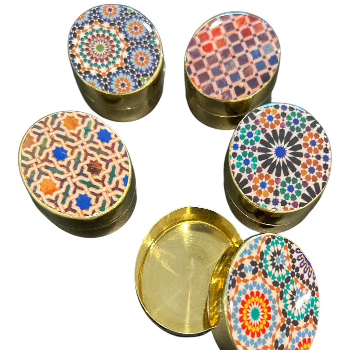 Set of decorative containers with colorful geometric patterns on lids and gold base.