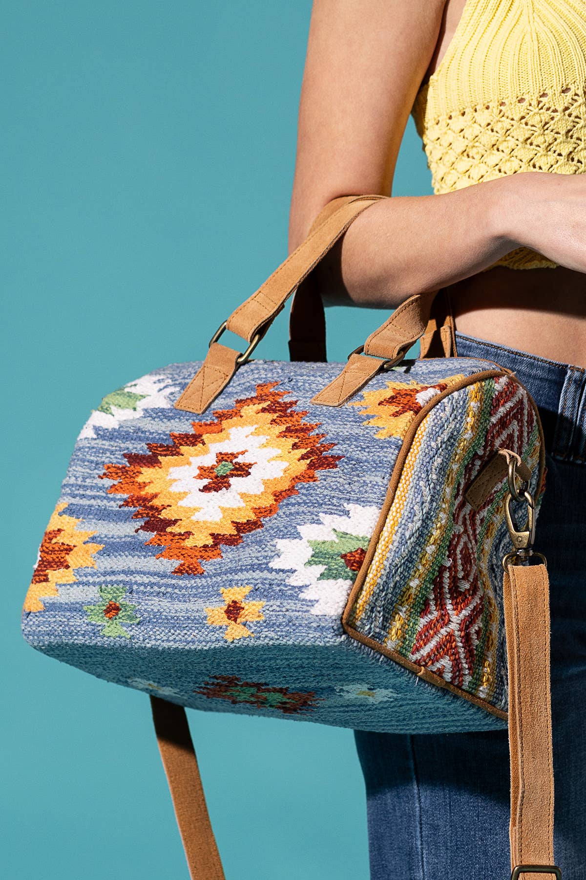Colorful patterned bag with brown strap on a purple background