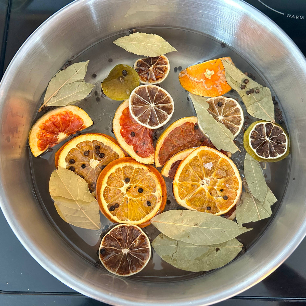 Dried citrus slices and bay leaves in a pot on a stove