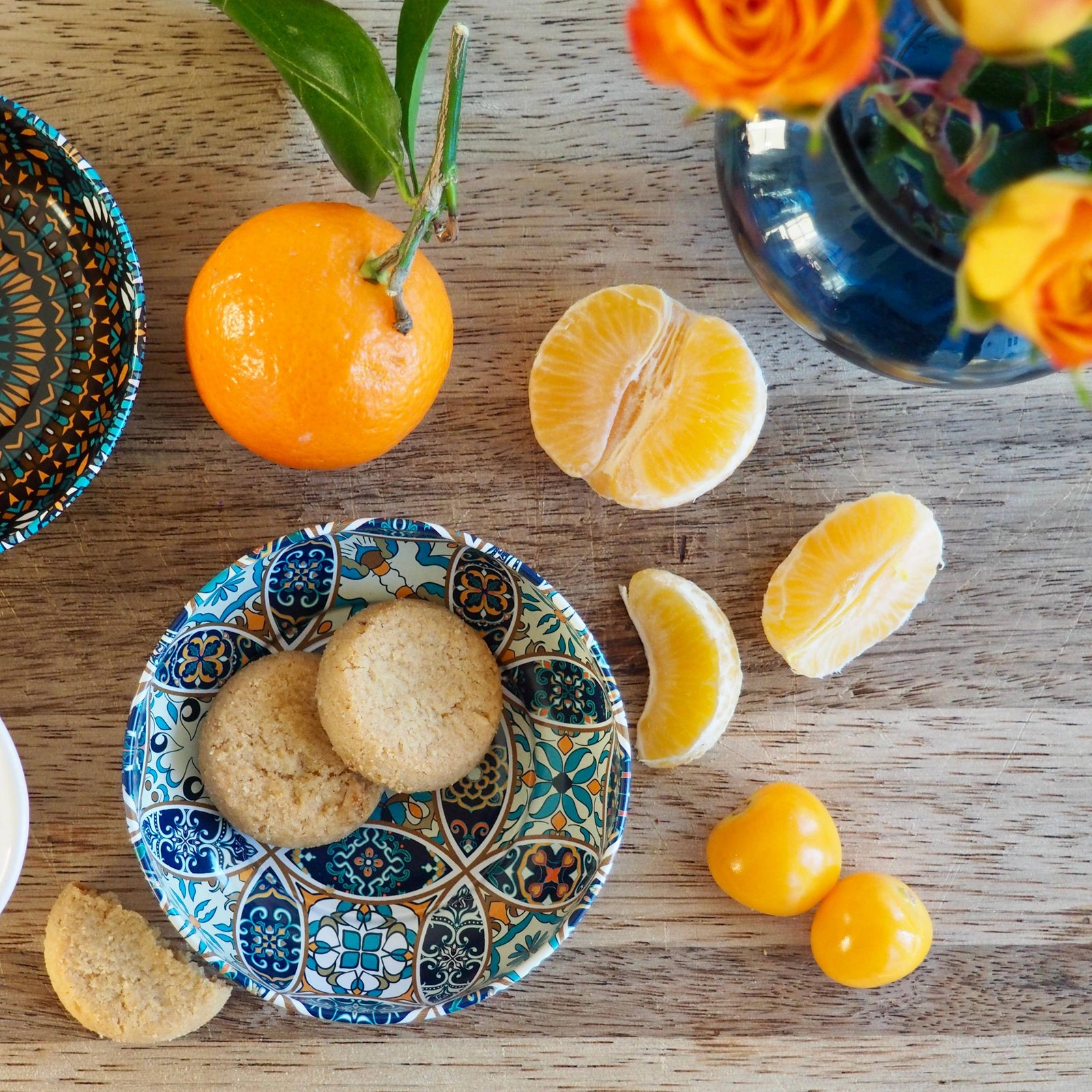 Assorted fruits and cookies on a wooden surface with a decorative bowl.