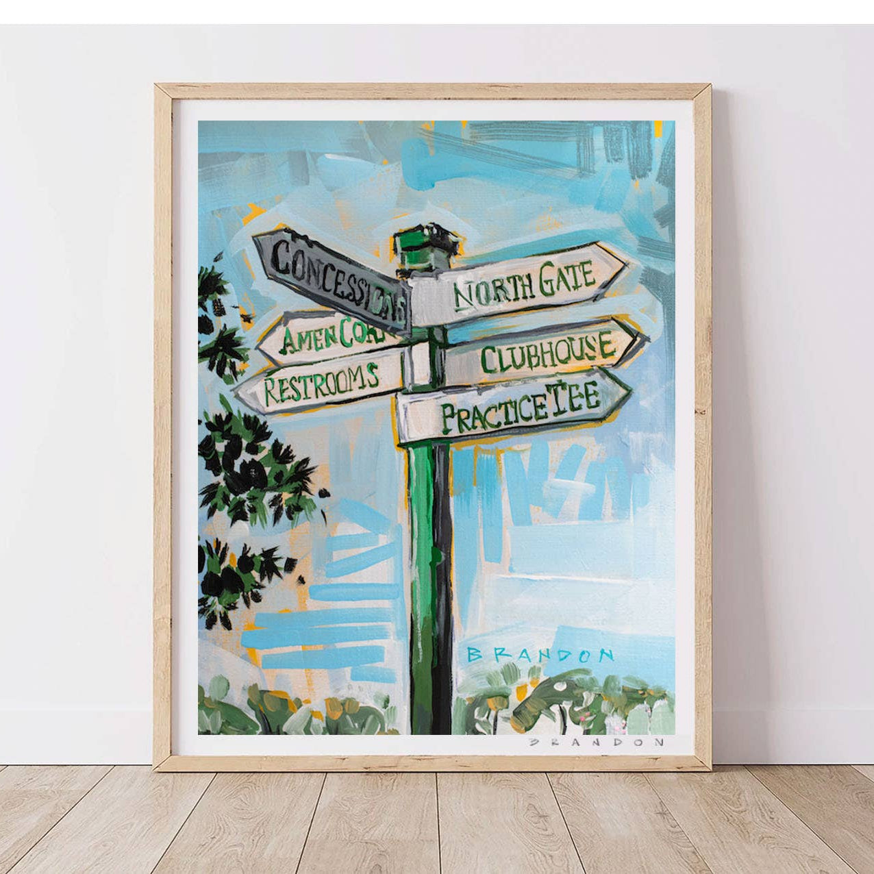 Framed artwork of a signpost with directional arrows on a white wall.