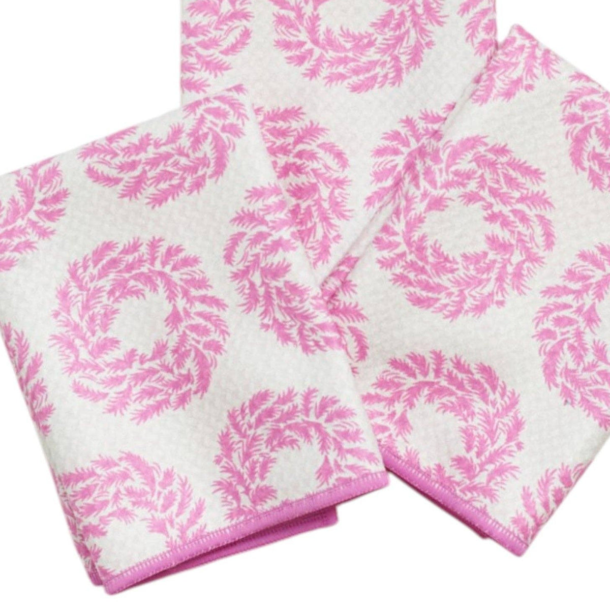 Three folded white towels with a pink woven floral wreath pattern and solid pink edges, arranged on a plain white background.