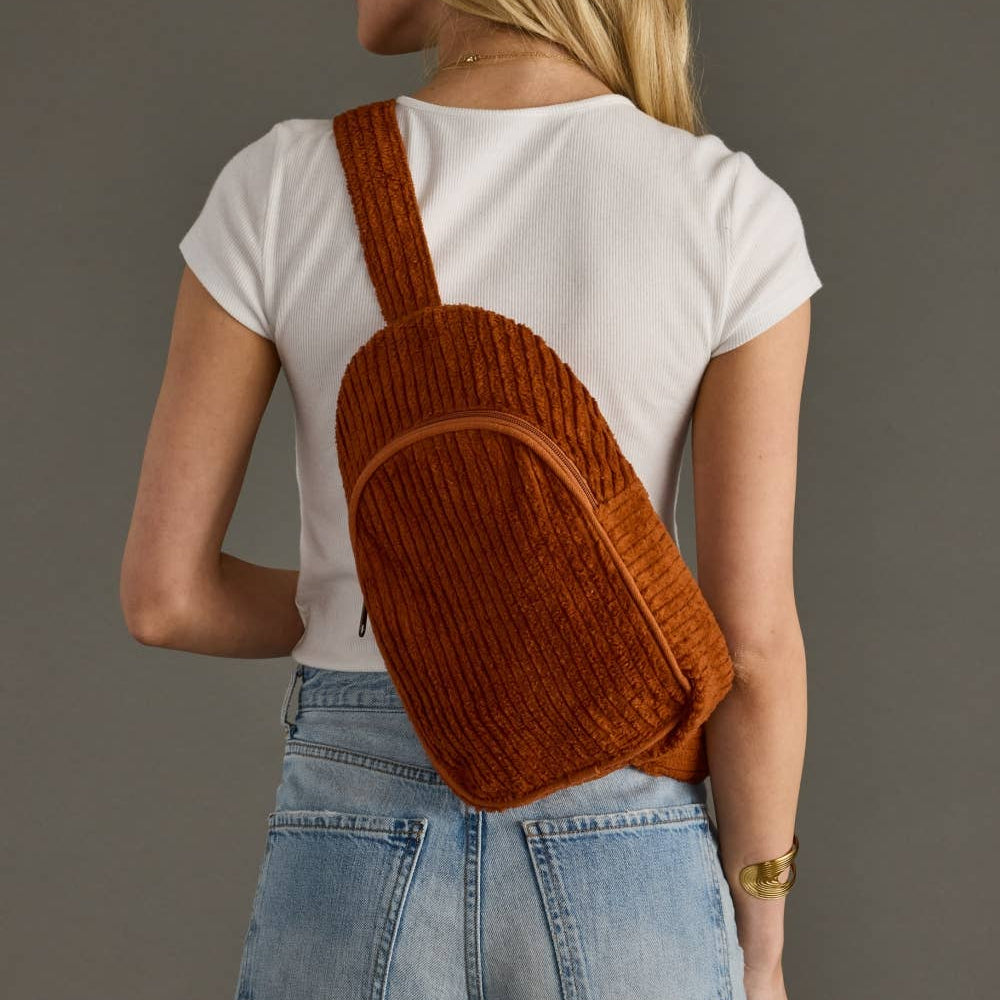 Person wearing a brown corduroy backpack against a gray background