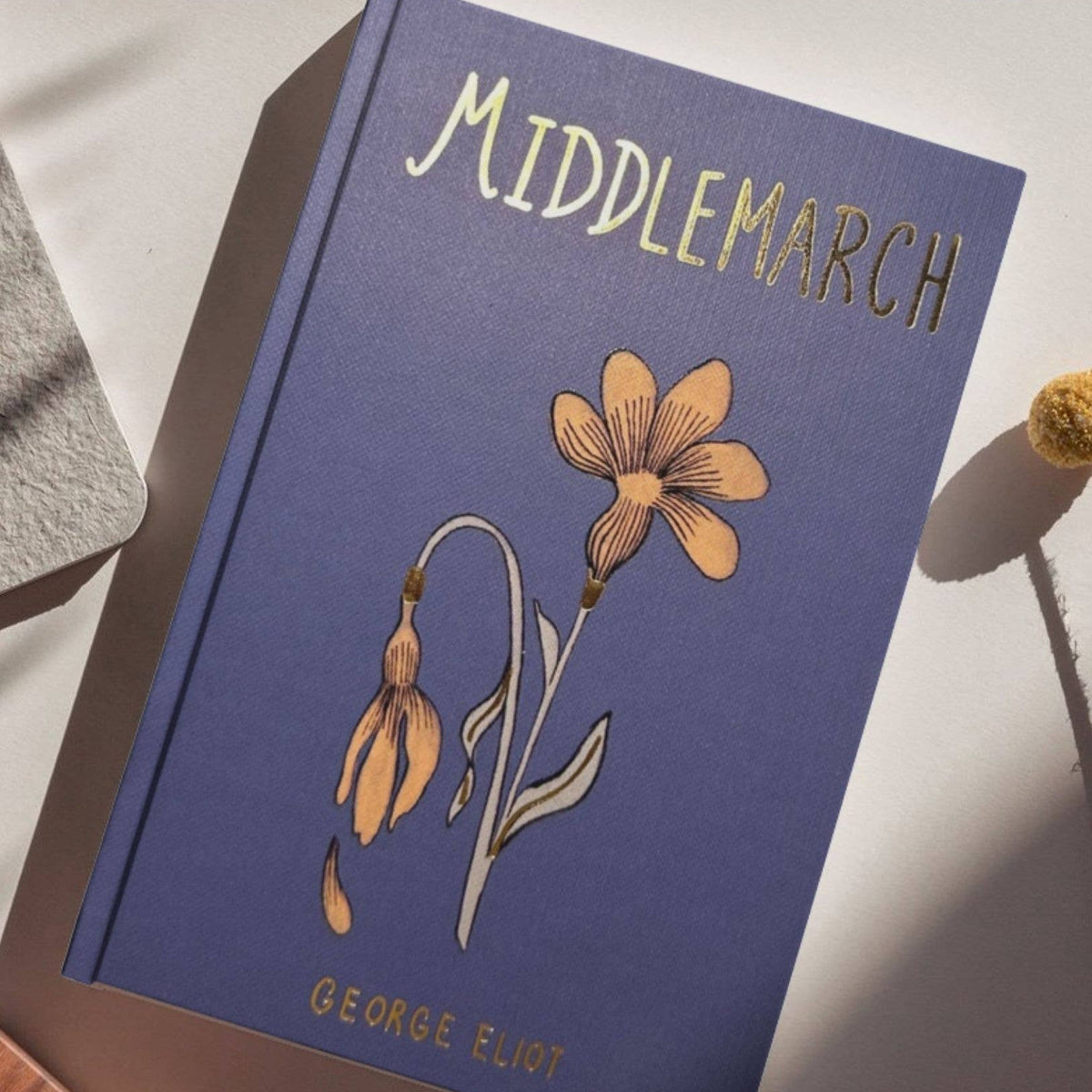 Book titled 'Middlemarch' by George Eliot with floral illustrations on a white surface.