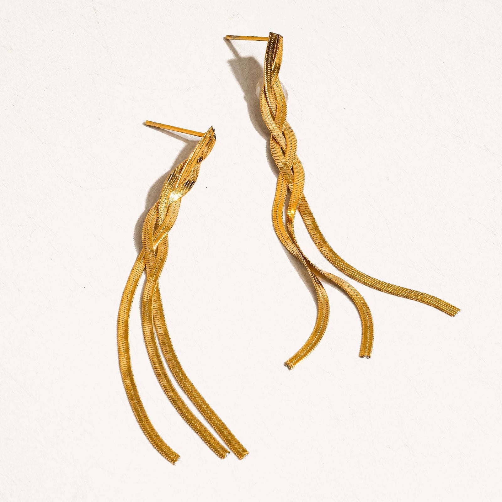 Gold braided earrings on a white background