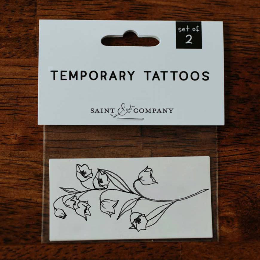 Pack of temporary tattoos with a card labeled 'Saint & Company' on a wooden surface