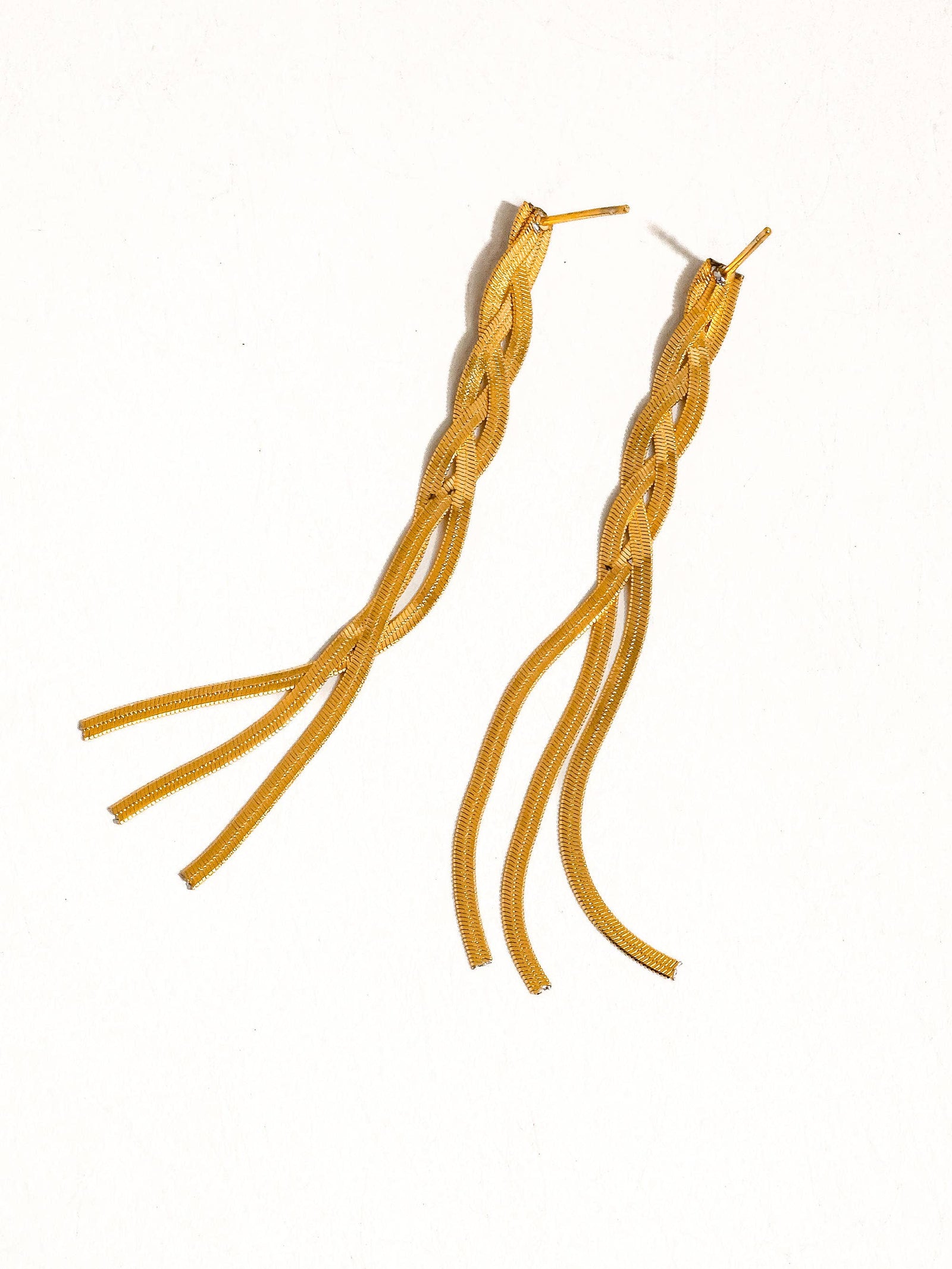 Gold braided earrings on a white background