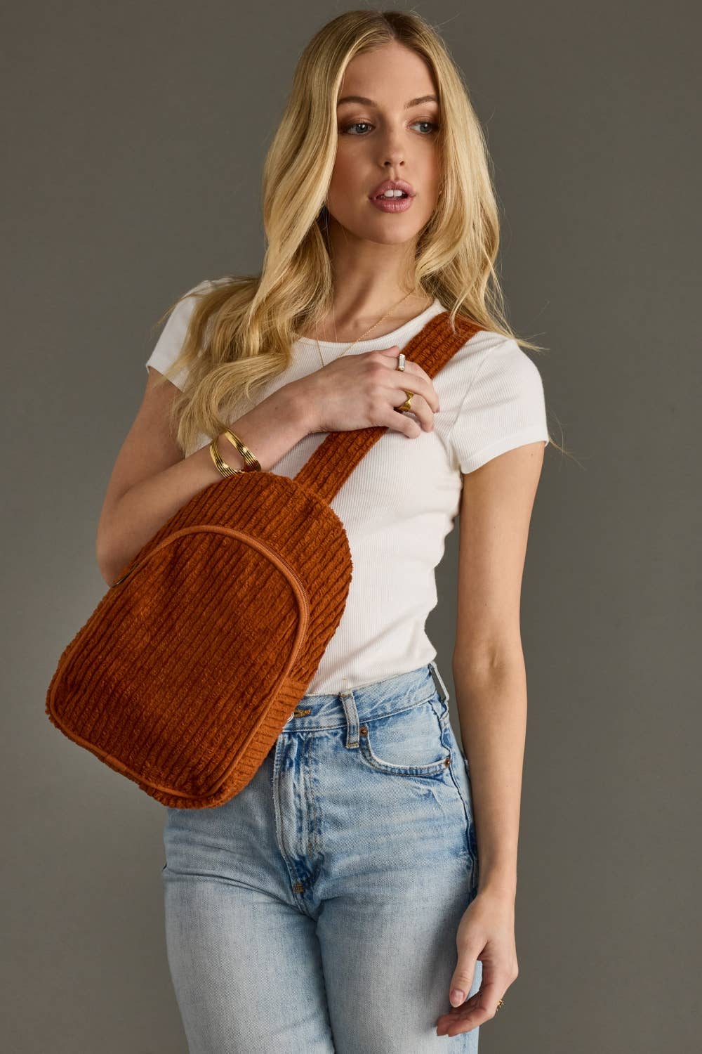 Person wearing a brown corduroy backpack against a gray background