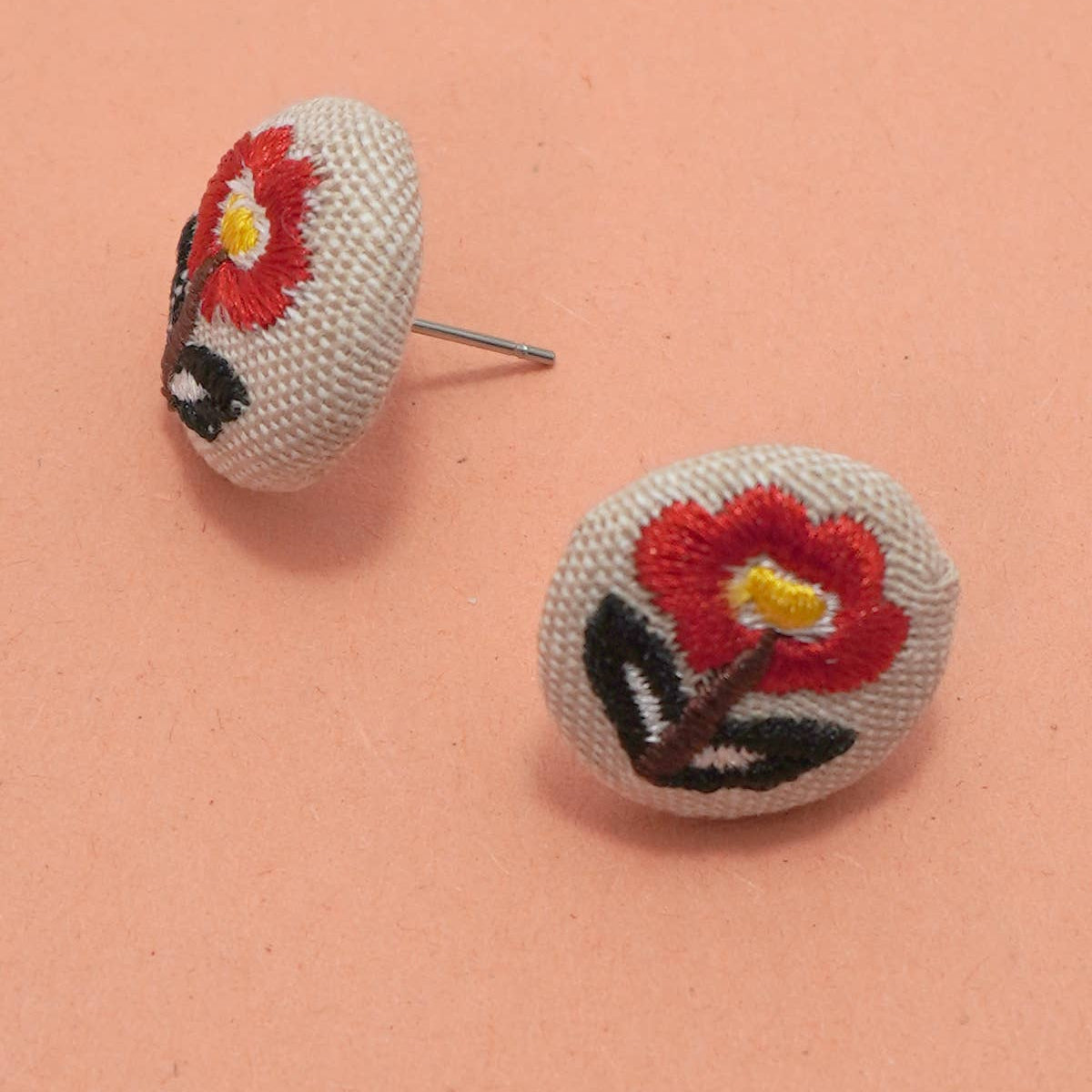 Floral embroidered earrings on a peach background