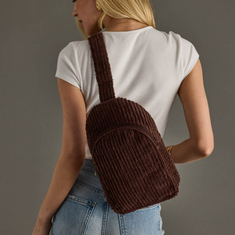 Person wearing a brown knitted backpack against a plain background
