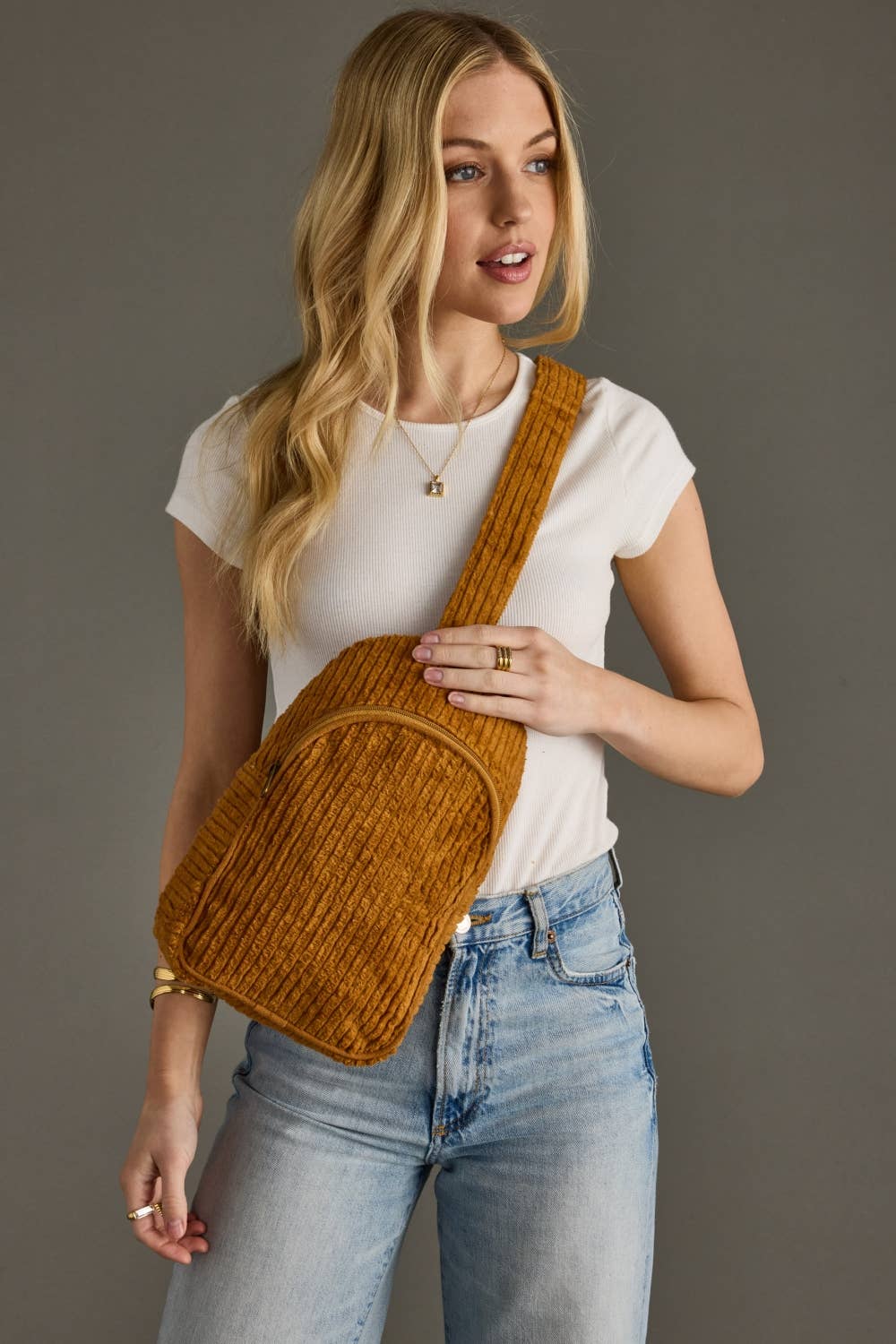 Person wearing a mustard yellow backpack against a gray background