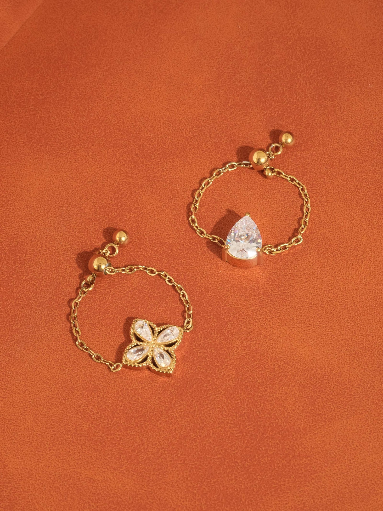 Gold bracelet with a teardrop-shaped crystal on an orange background