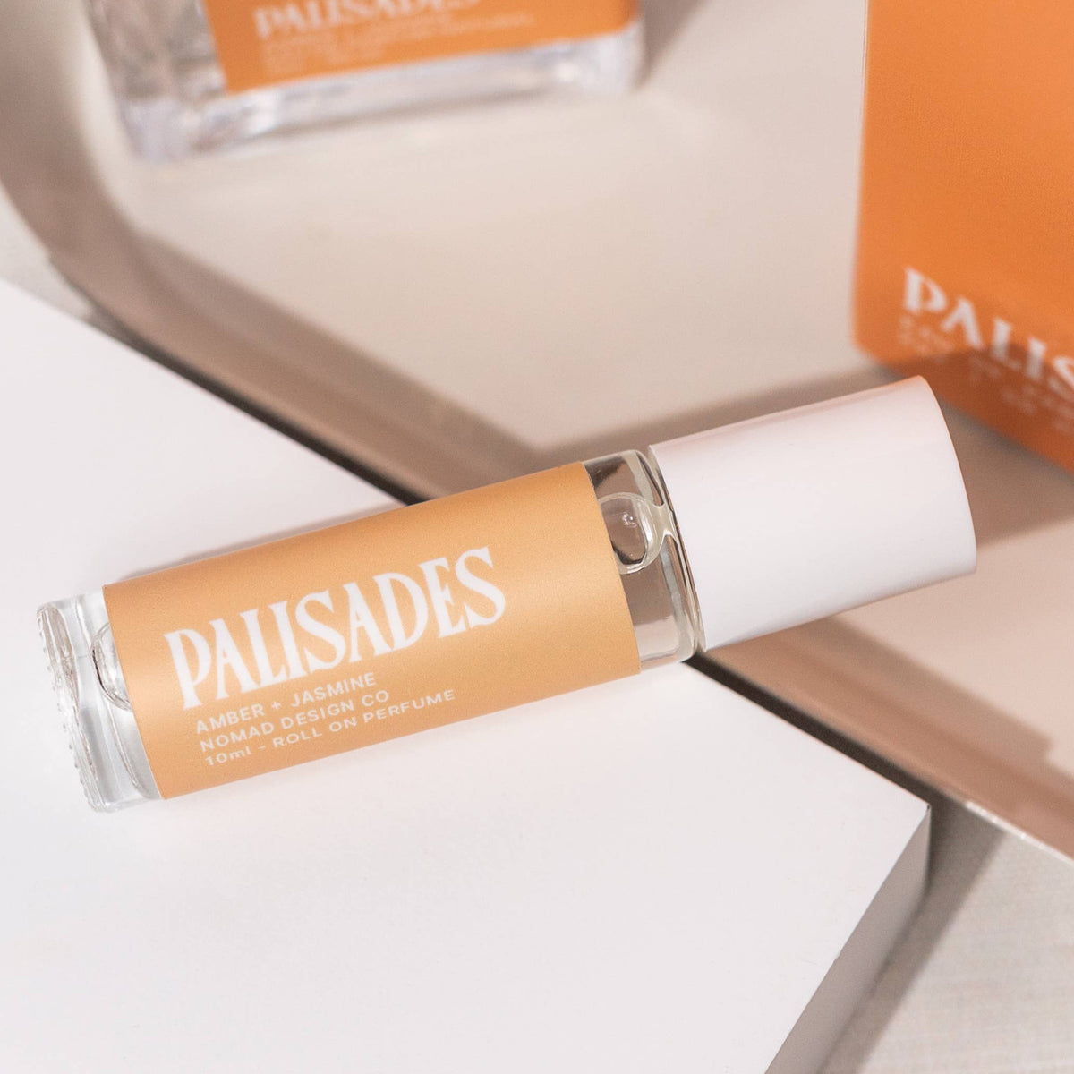 Roll-on perfume bottle and box with 'PAUSADES' branding on a light background