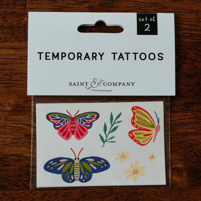 Butterfly tattoos on a person's arm and hand against a neutral background