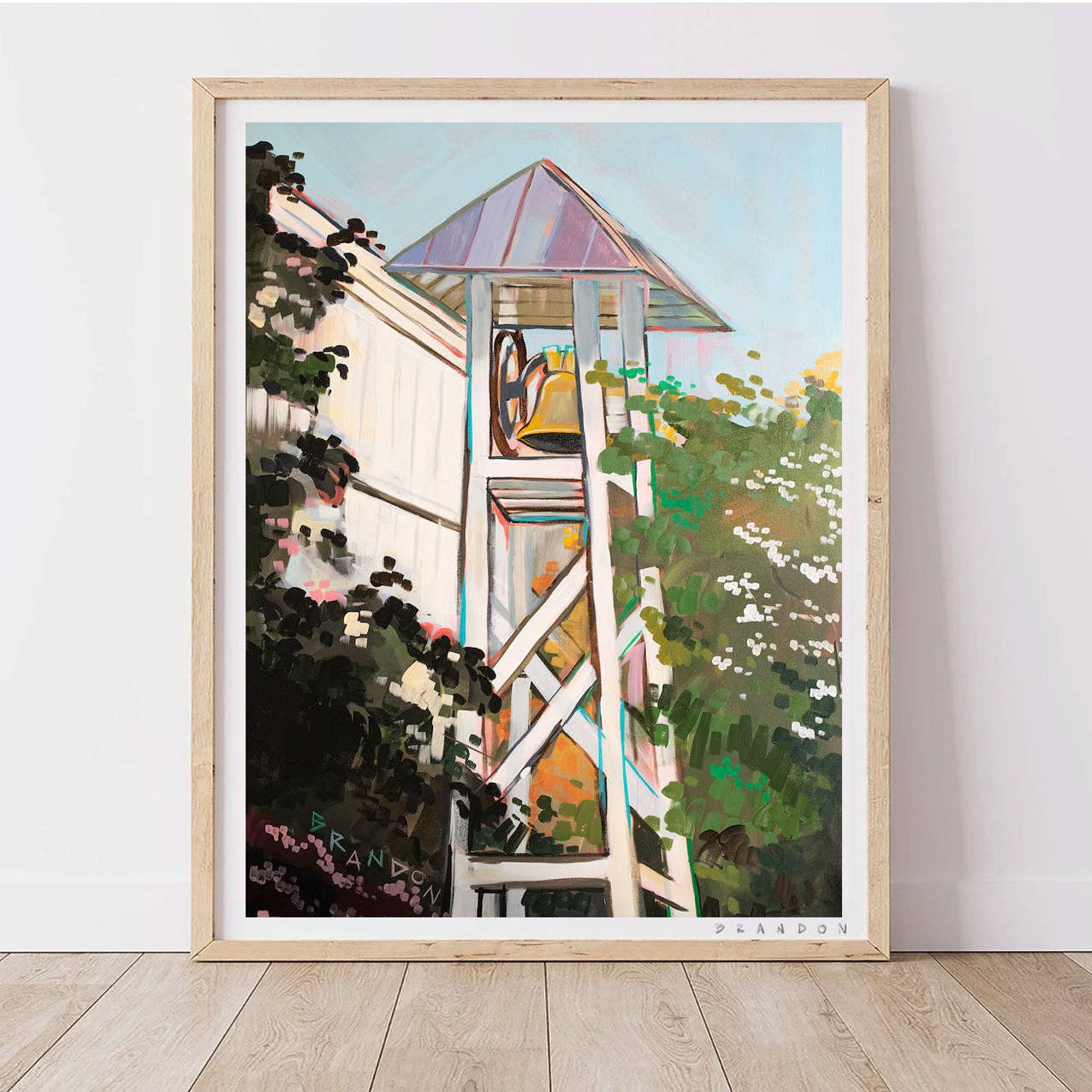 Framed artwork of a bell tower with plants on a white wall.