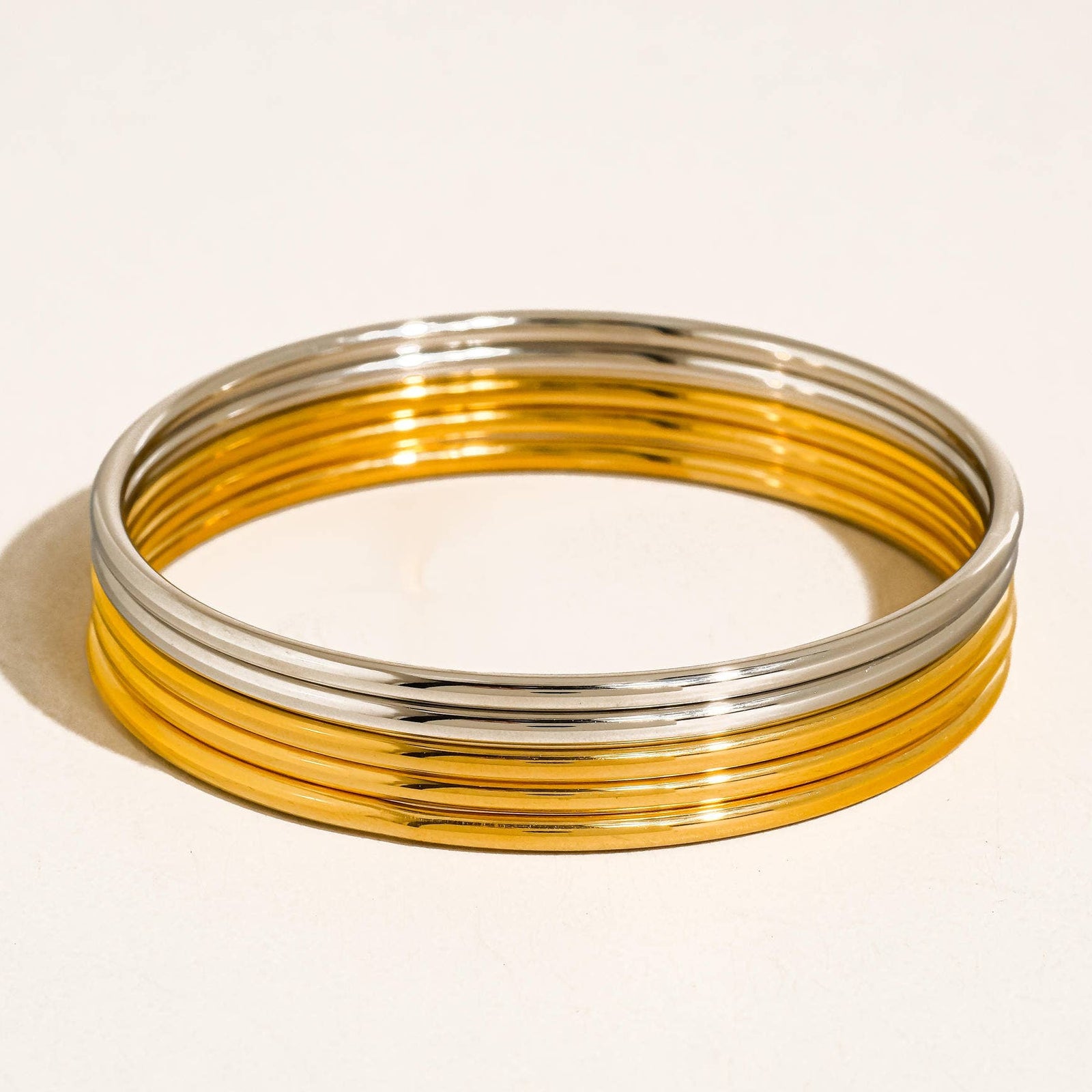 Set of gold and silver bangles on a light beige background