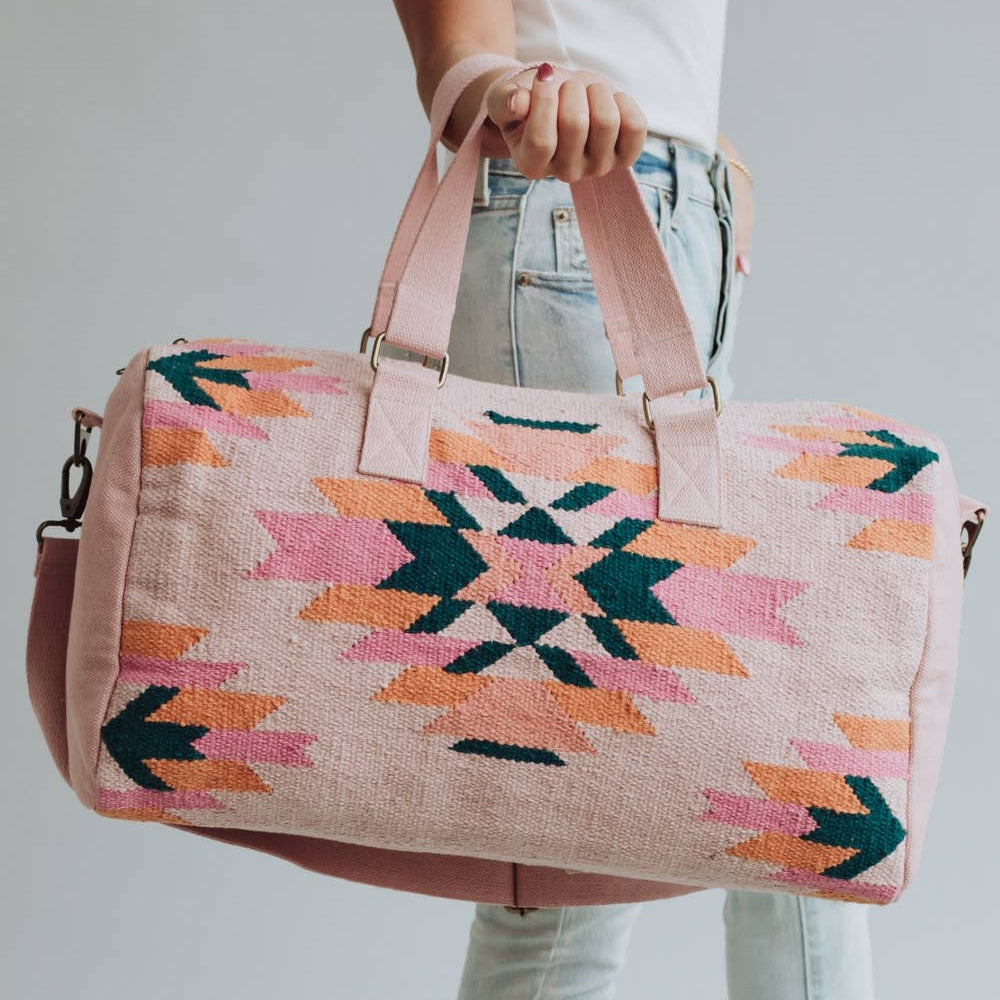 Person holding a colorful patterned bag against a plain background