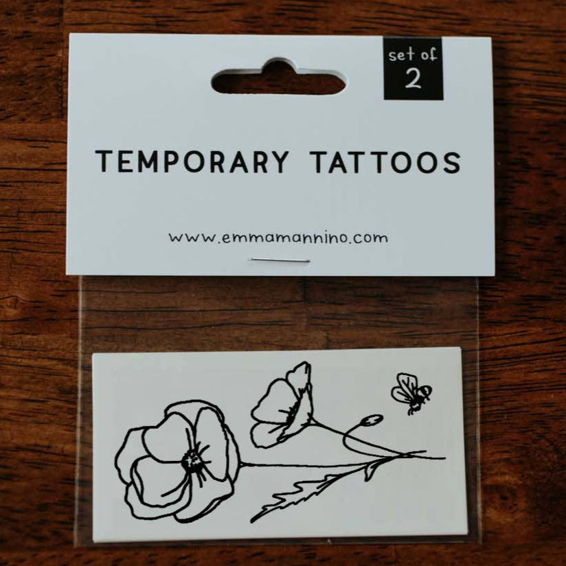 Close-up of feet with floral tattoos on a textured floor.