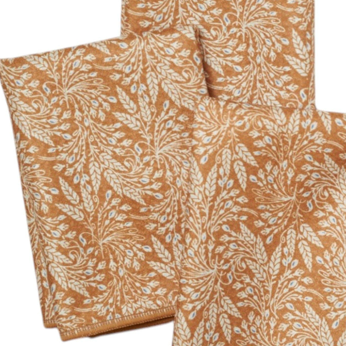 Three folded fabric napkins with a leaf pattern on a white background
