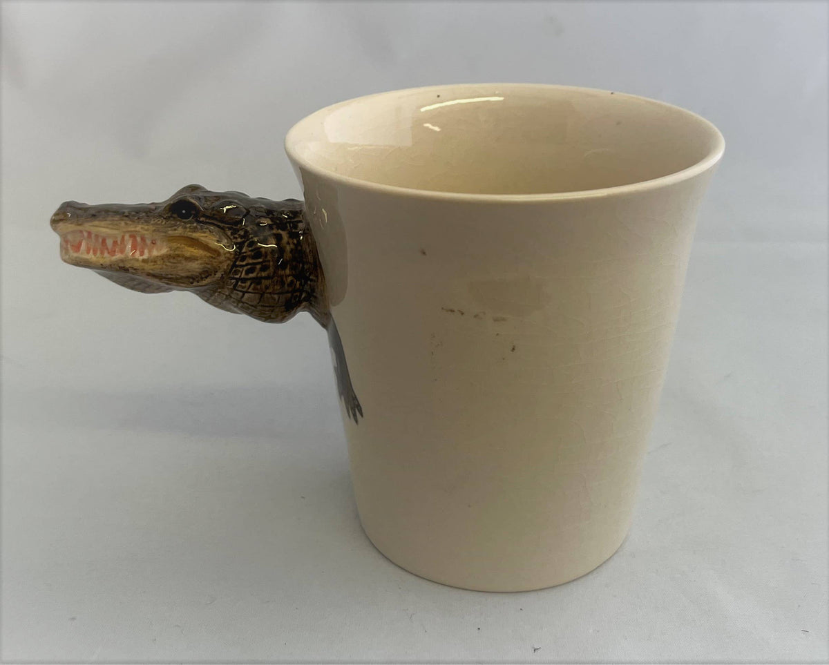 Beige mug with a crocodile head handle on a white background